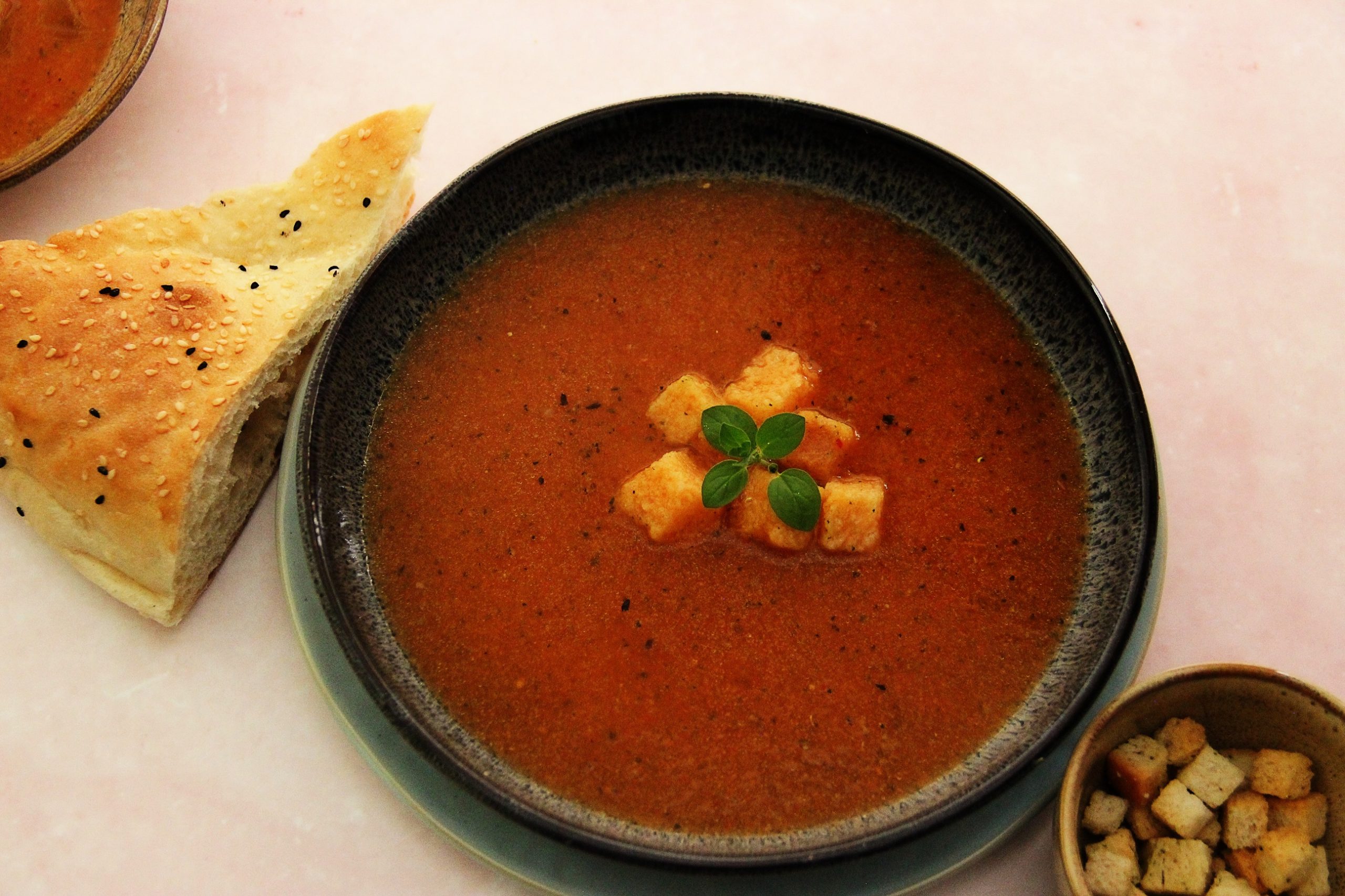 Geröstete Gemüsesuppe mit Croutons und Brot serviert.