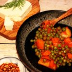 Arakas laderos angerichtet in einem tiefen schwarzen Teller, dabei Feta und Chili.