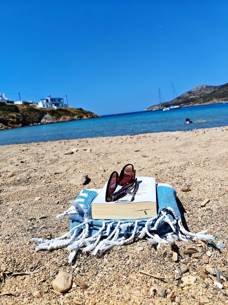 Ein Handtuch am Strand von Lipsi mit Buch und Sonnenbrille drauf.