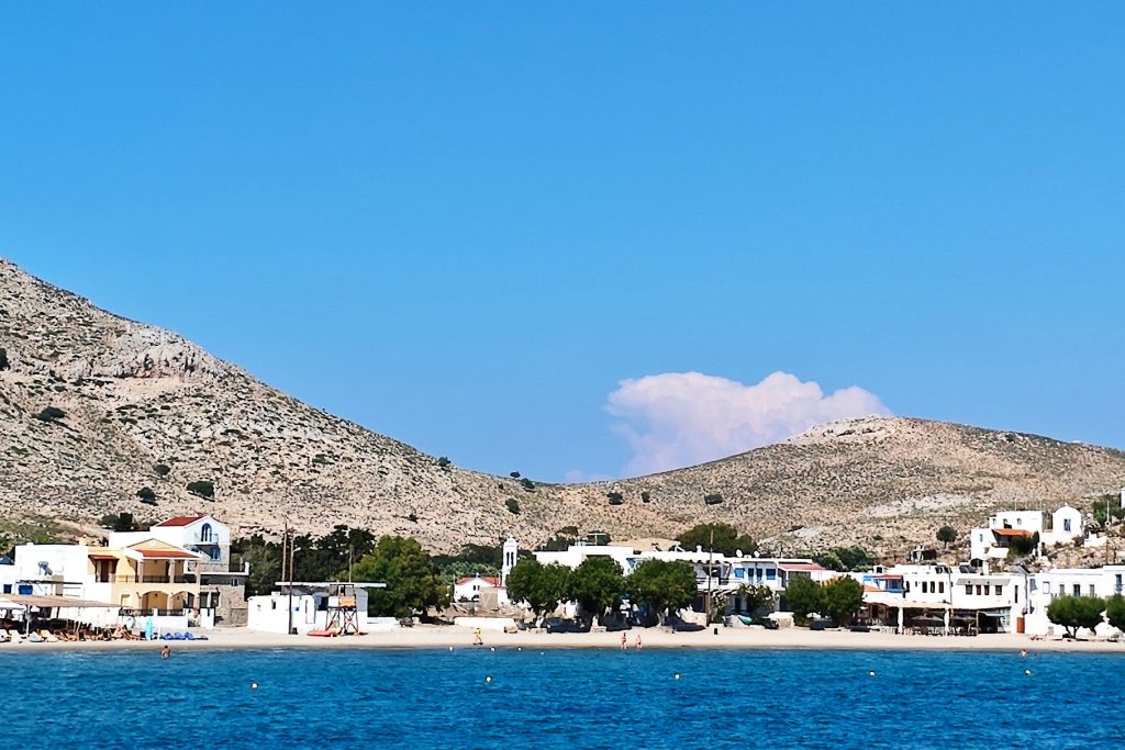 Vom Meer aus blickt man auf die Häuser, den Strand und die Berge von Pserimnos.