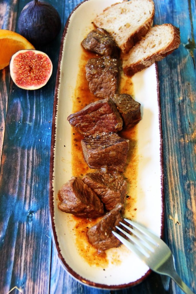 Rindfleisch mit Feigen und Orange mit Brot und Bratensud angerichtet.